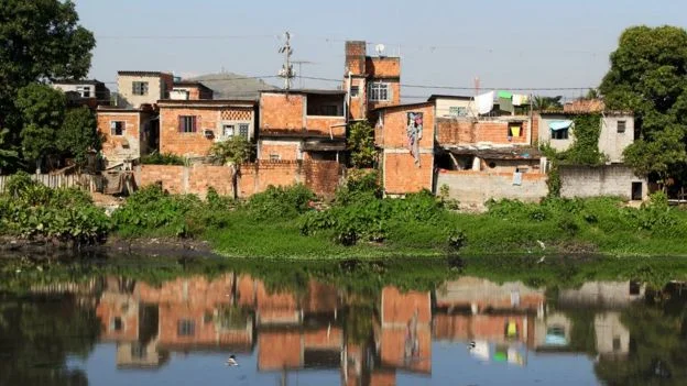 Casas precárias, sem pintura, na beira de canal poluído no Rio de Janeiro