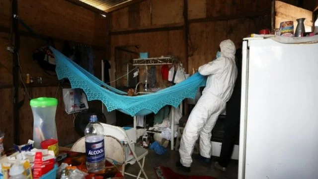 Profissional de saúde avalia corpo de mulher que morreu em casa por covod-19