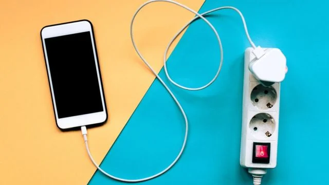 Celular carregando com carregador ligado em uma régua