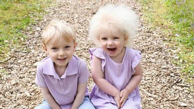 Freddie e Layla sorrindo sentados em jardim