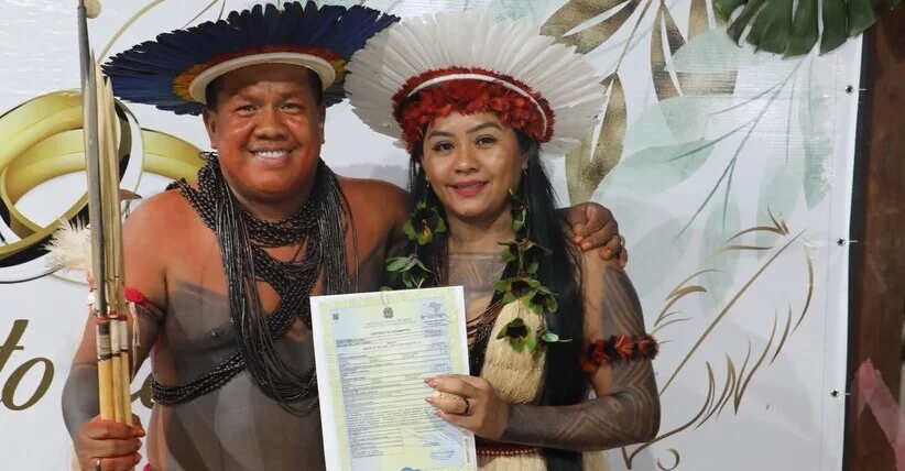 A foto colorida mostra indígenas com certidão de casamento em mãos 