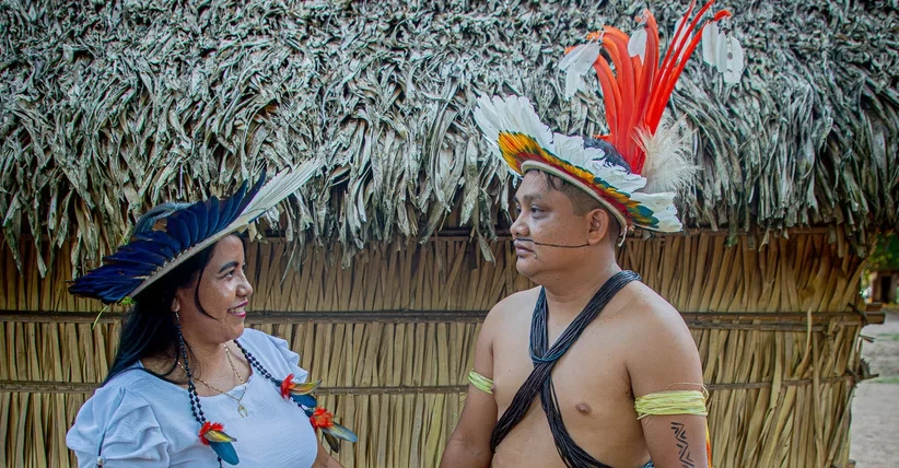 A foto colorida mostra casais indígenas se olhando 