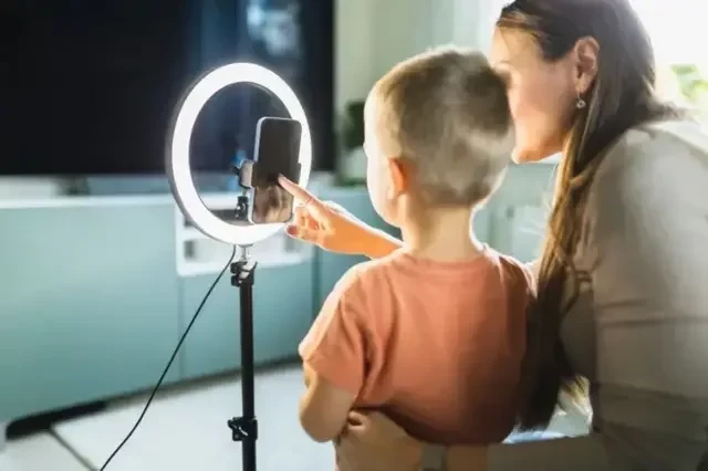 Mãe ao lado de um filho colocando o celular para gravar um conteúdo