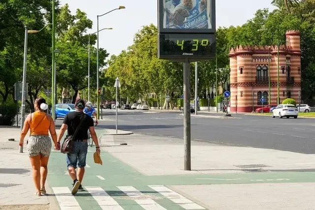 Pessoas andando na rua. Há um monitor de temperatura que registra 43 graus Celsius. 