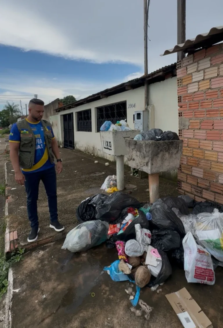 Um bebê sorri e estende a mão em direção à câmera enquanto está deitado com uma manta macia sobre o peito.