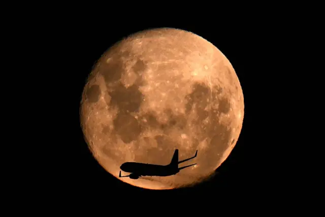 Avião passando em frente à Lua.