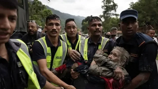 Policiais transportam uma idosa que sobreviveu à enchente repentina em Trishuli, no distrito de Nuwakot, no Nepal.