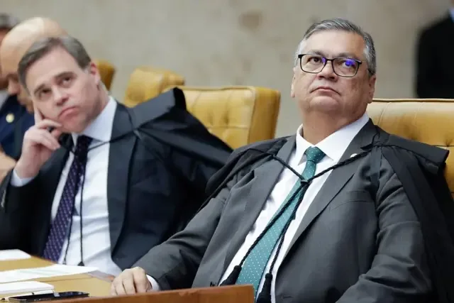 André Mendonça e Flávio Dino sentados no plenário no STF olham para cima