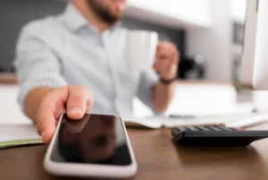 Pessoa à mesa com celular e calculadora