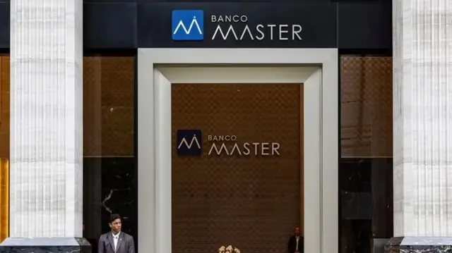 Segurança em frente a portal de entrada com logo do Banco Master