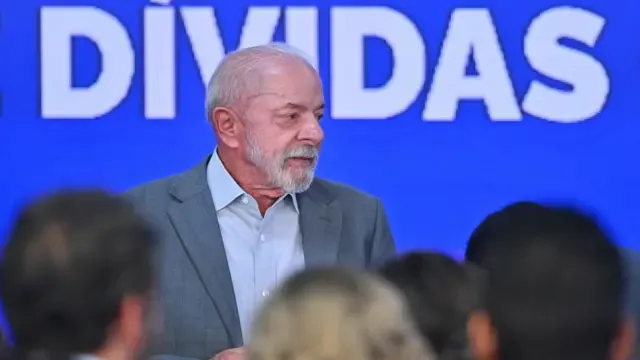 Lula em frente a um painel de LED os se lê: "Dívidas"